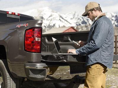 man using laptop on the tailgate of his truck