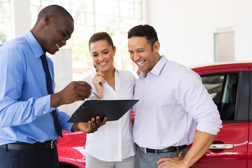 Salesman showing couple forms for buying a used car