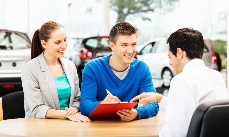 Happy couple at dealership finalizing financing