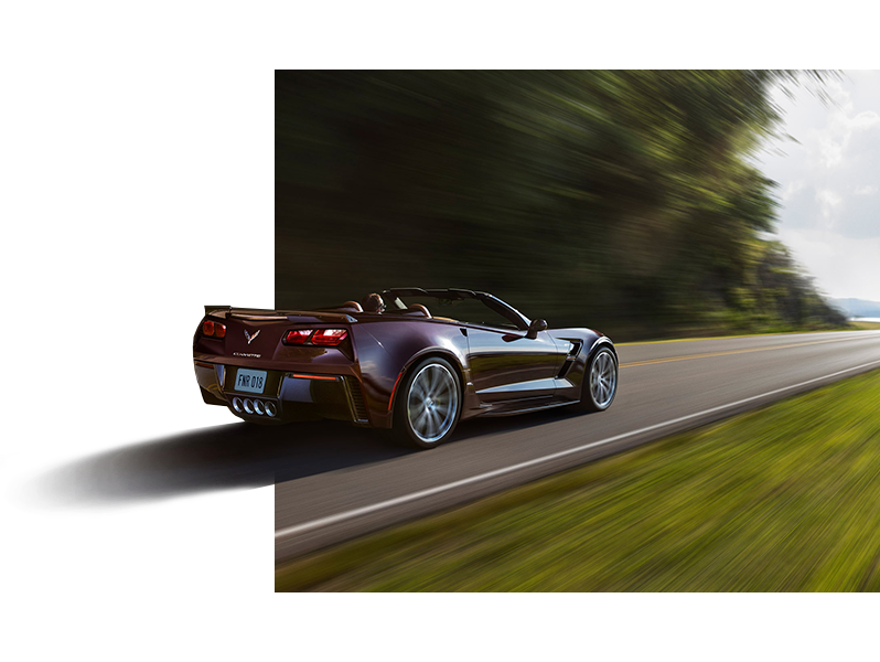 Burgundy Corvette driving on a road Burgundy Corvette driving on a road
