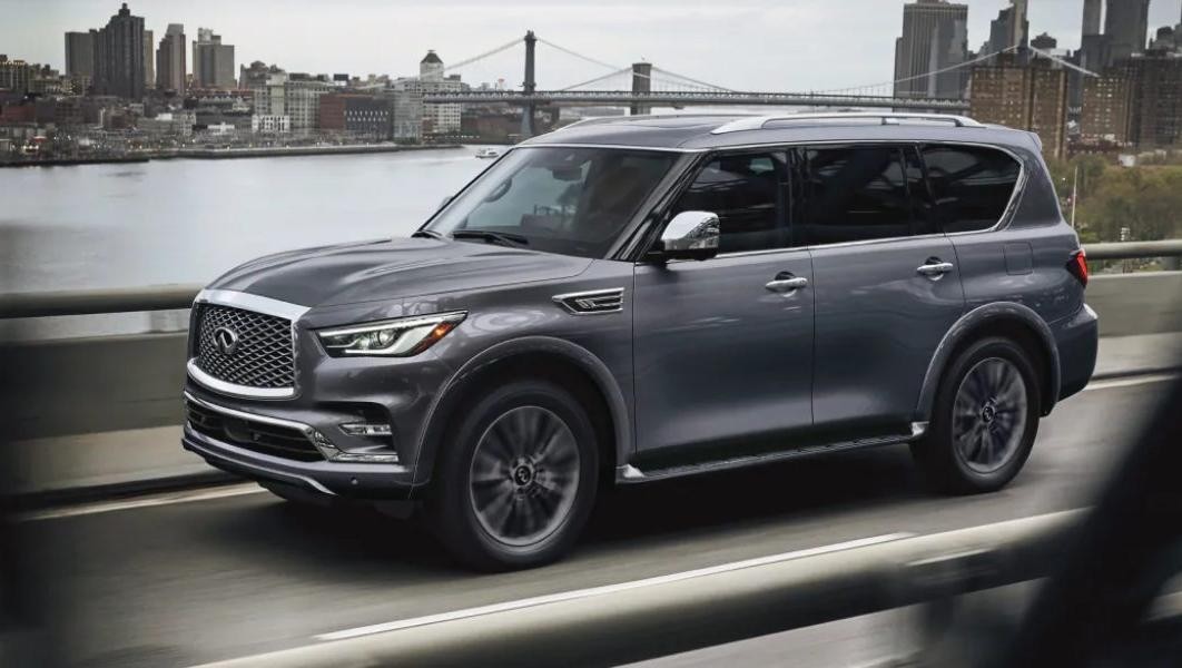 2024 Infiniti QX80 driving across a bridge in a city