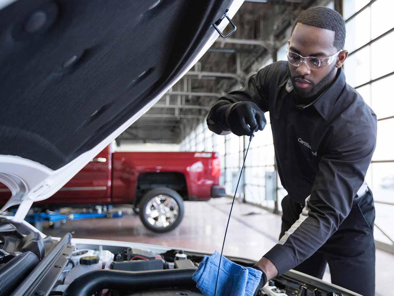 Service technician checking vehicle oil Service technician checking vehicle oil