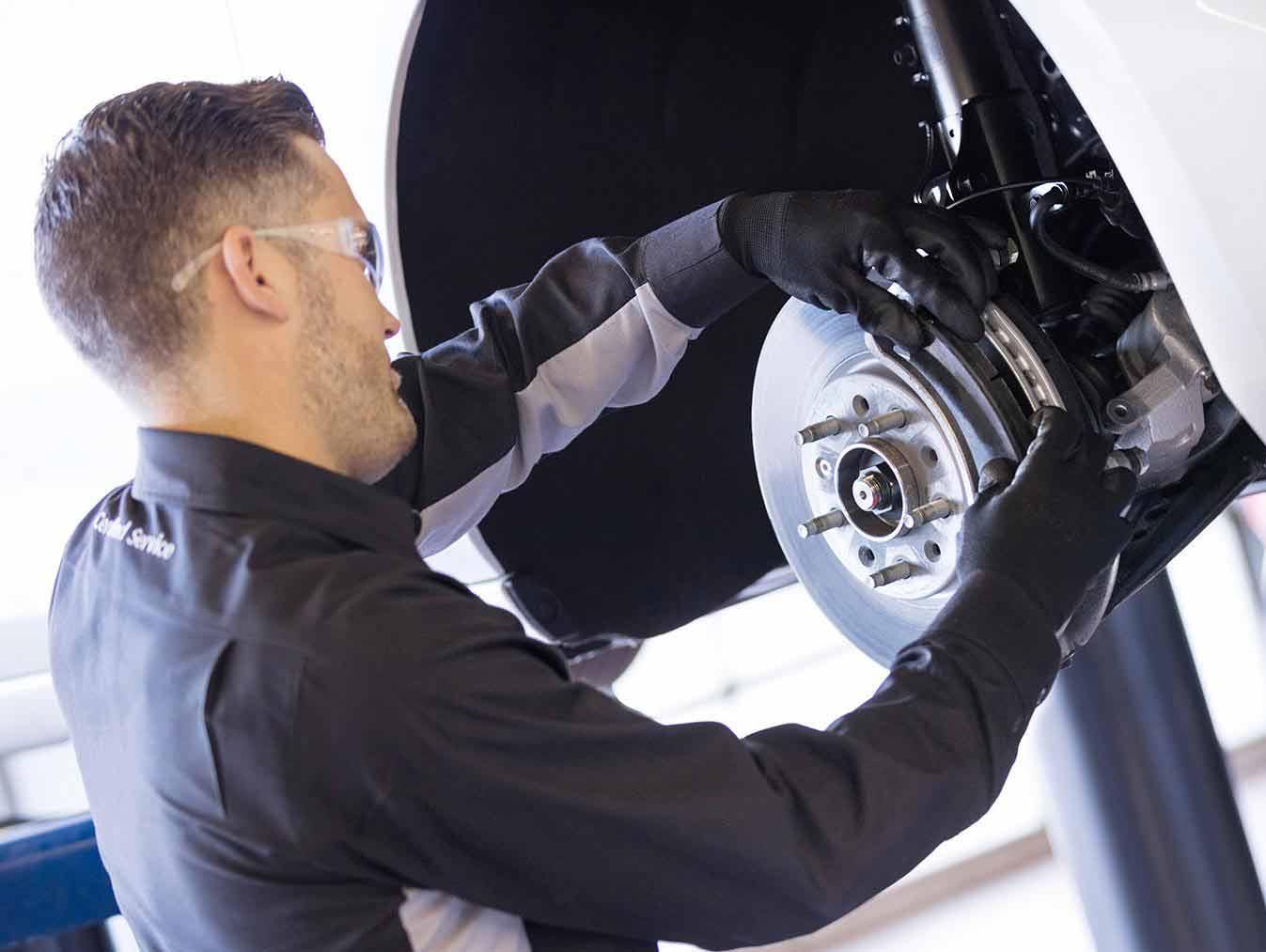 Service technician changing brake pads Service technician changing brake pads