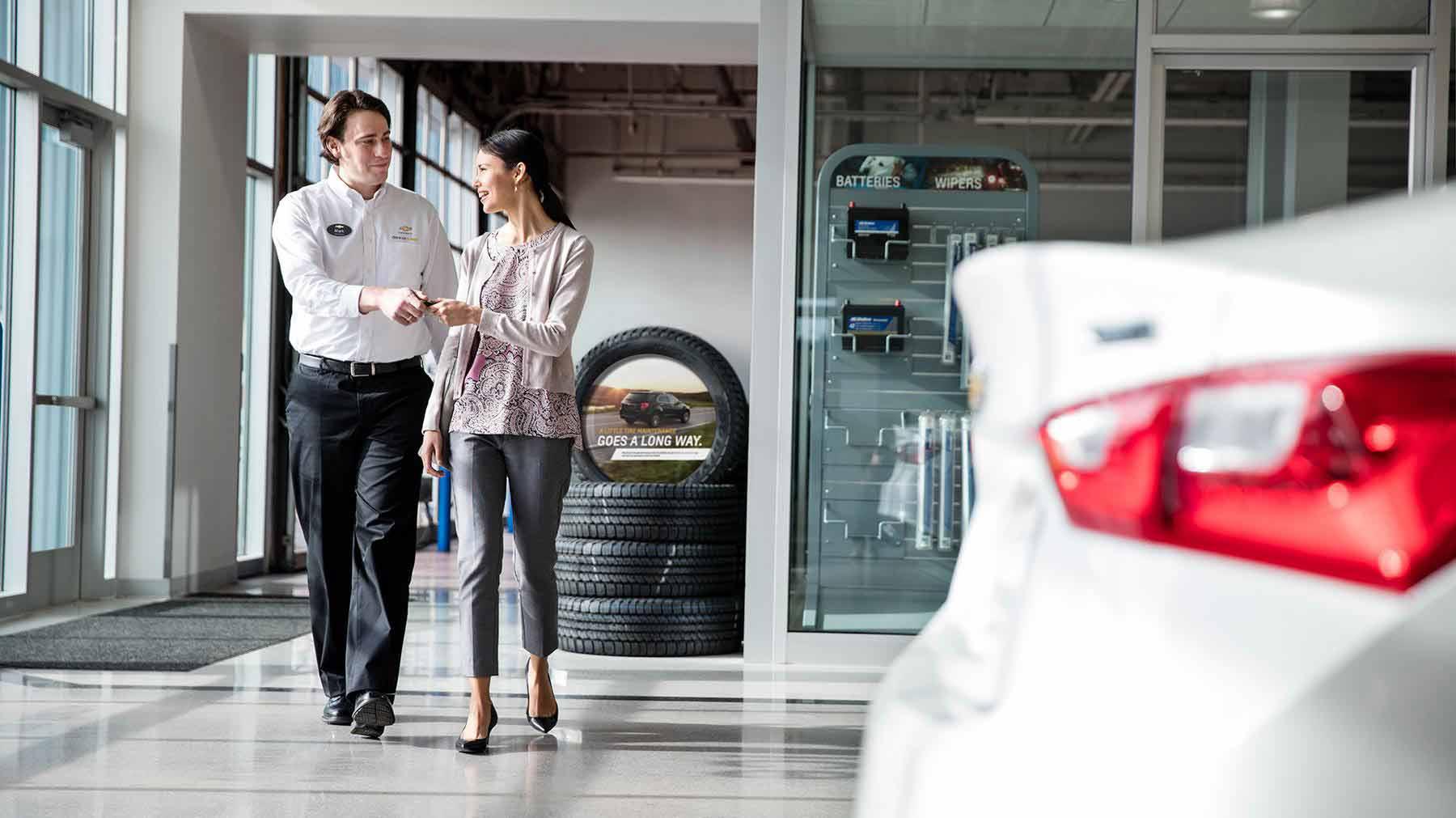Chevrolet Certified Service Employee handing keys to women. Chevrolet Certified Service Employee handing keys to women.