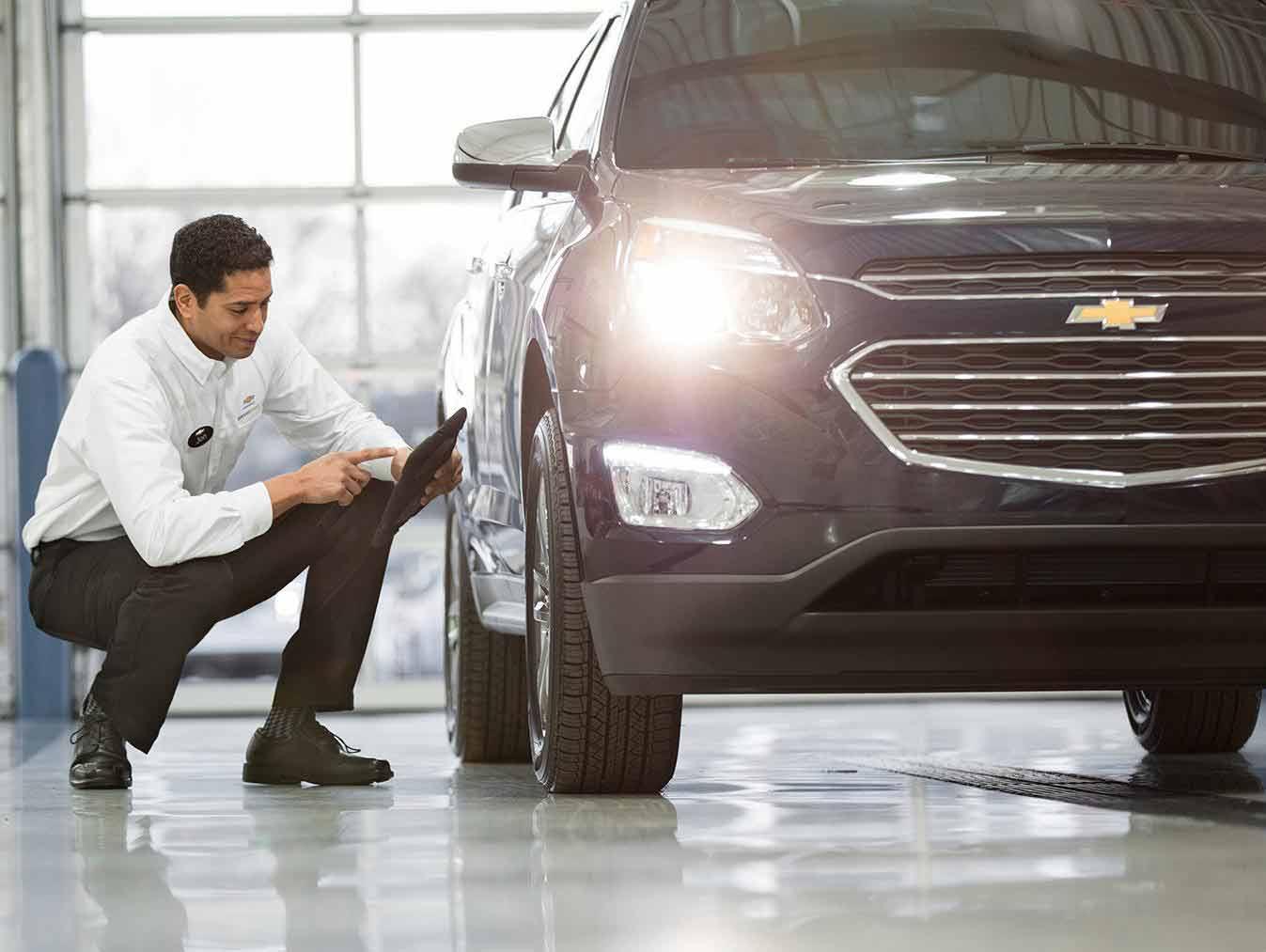Chevrolet Service technician checking on tires of SUV Chevrolet Service technician checking on tires of SUV
