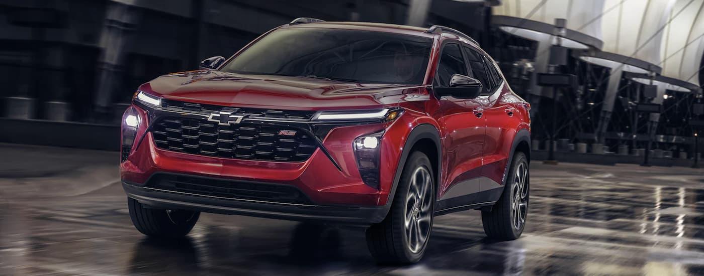 A red 2024 Chevy Trax RS is shown from the front driving through a tunnel. A red 2024 Chevy Trax RS is shown from the front driving through a tunnel.