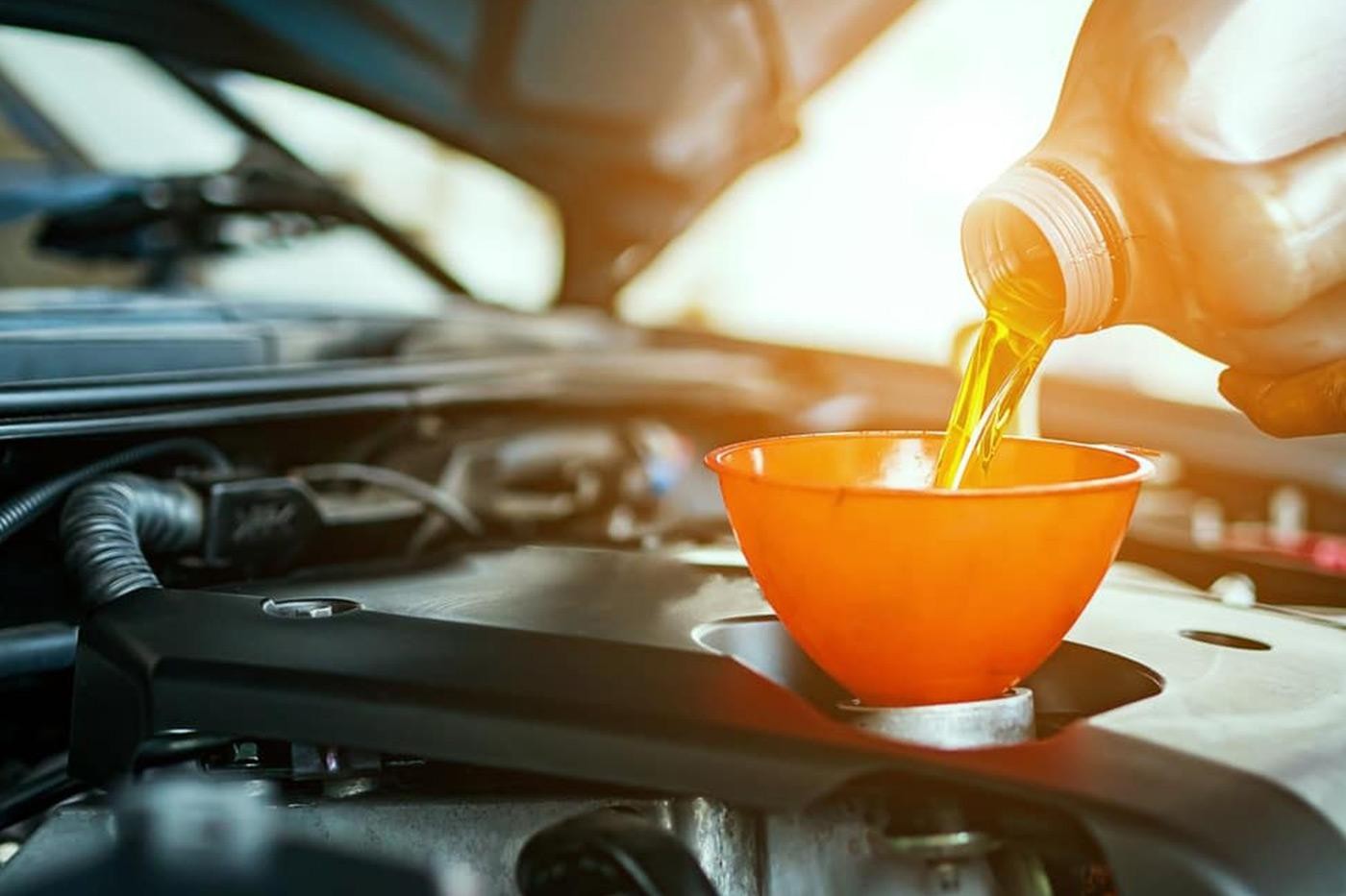 Pouring motor oil for motor vehicles from a gray bottle into the engine.