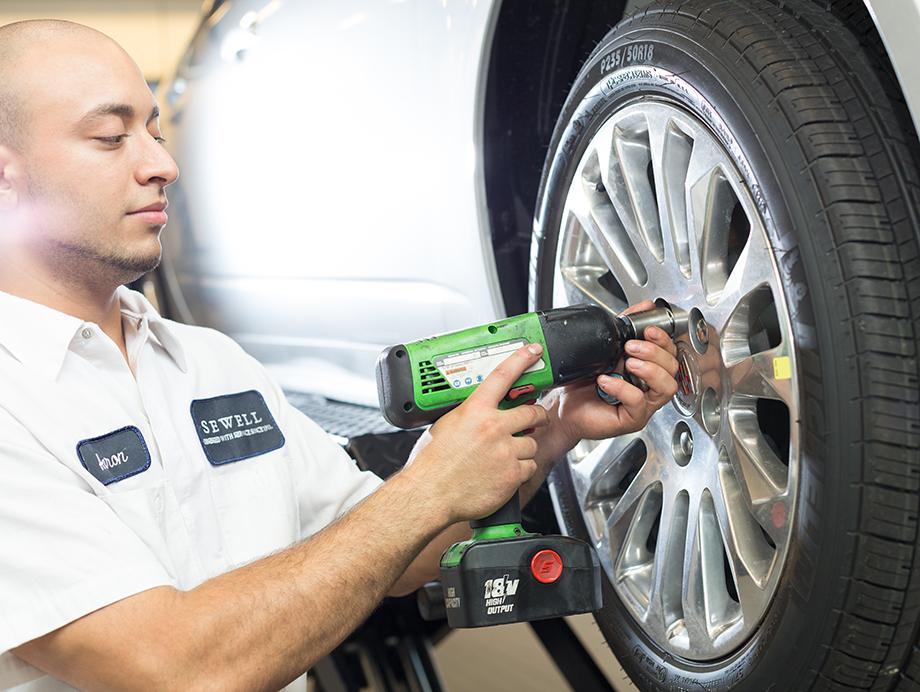 Technician tightening lug nut on tire with tool