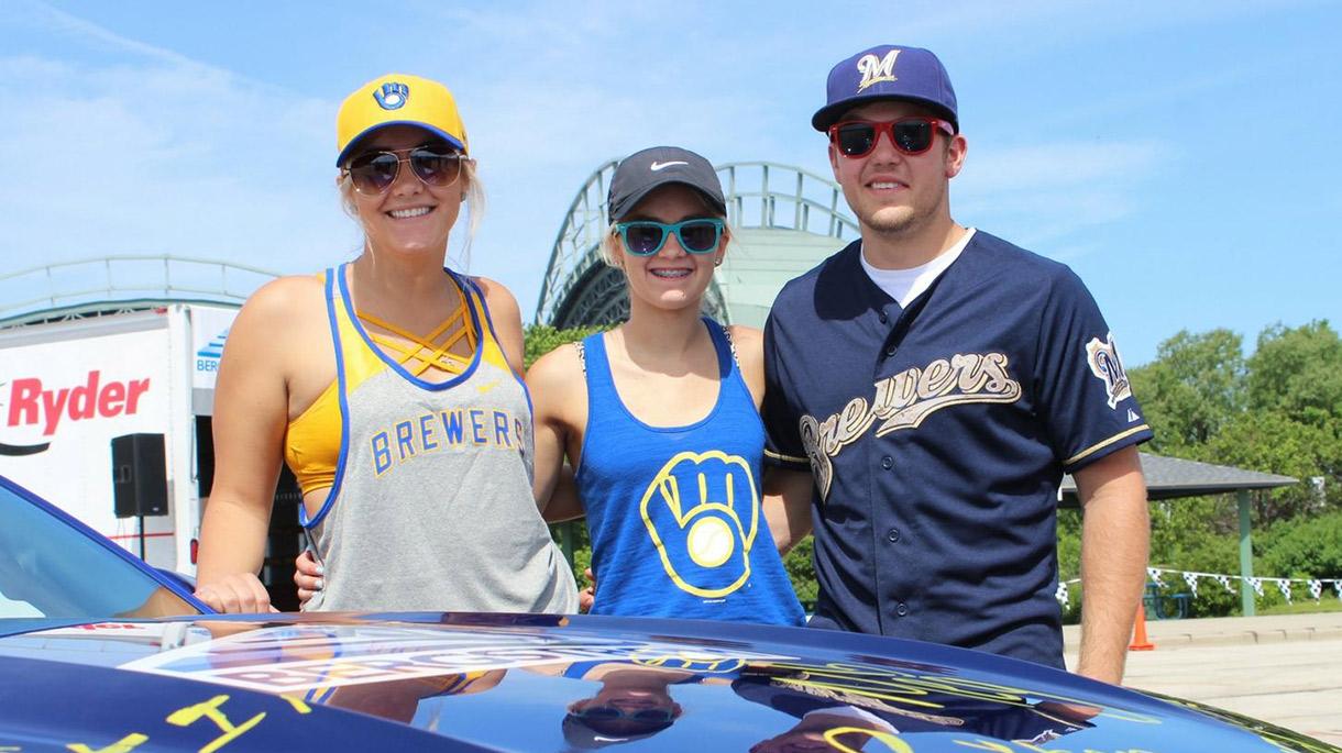 Three people in Milwaukee Brewers clothing near stadium