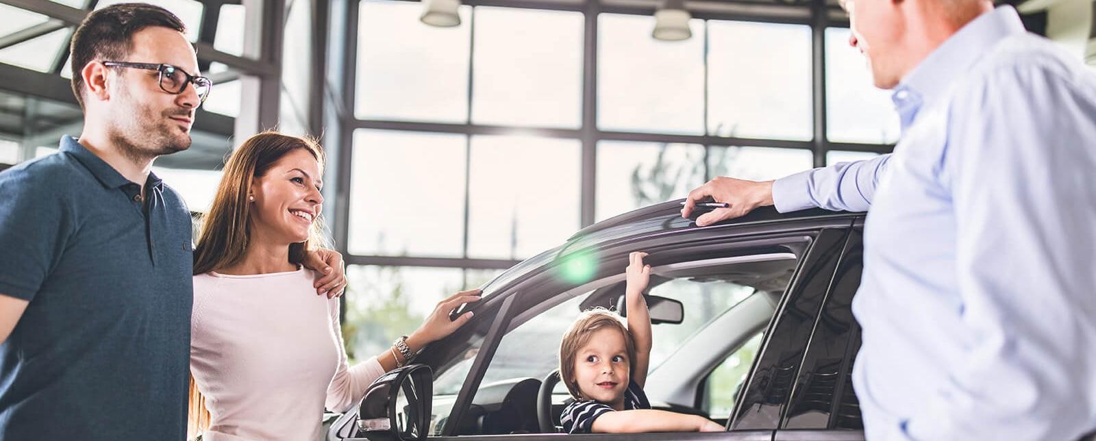 Smiling young family shopping for a new car
