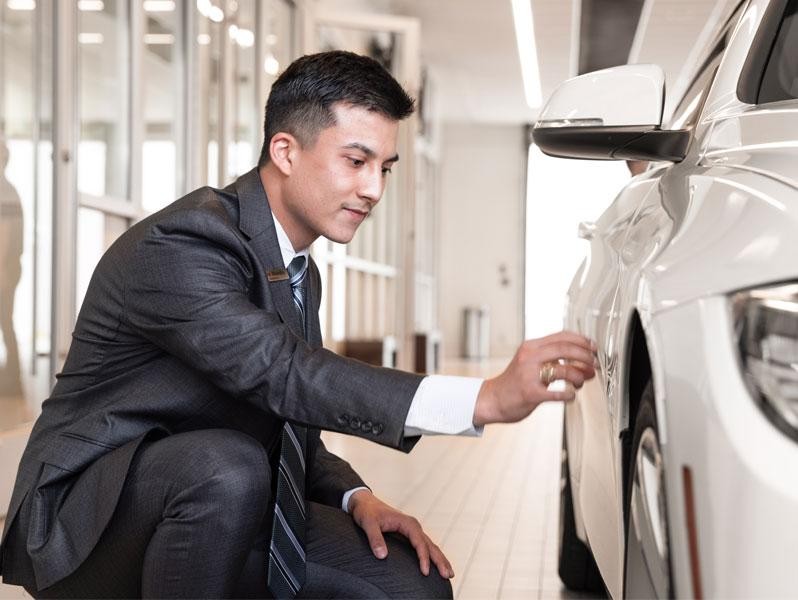 Sewell associate examining the exterior of a vehicle.