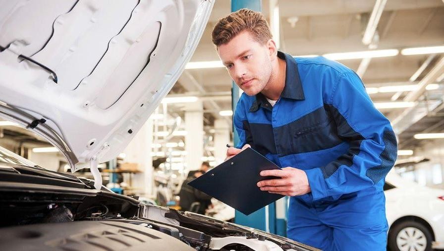 Mechanic holding clip-board servicing vehicle. Mechanic holding clip-board servicing vehicle.