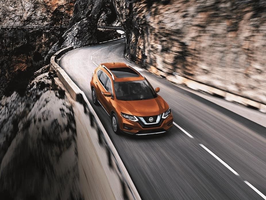 Orange Nissan Car cruising on. road in mountains