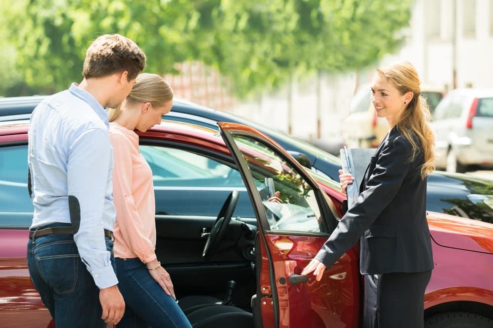 Saleswoman showing car to customer