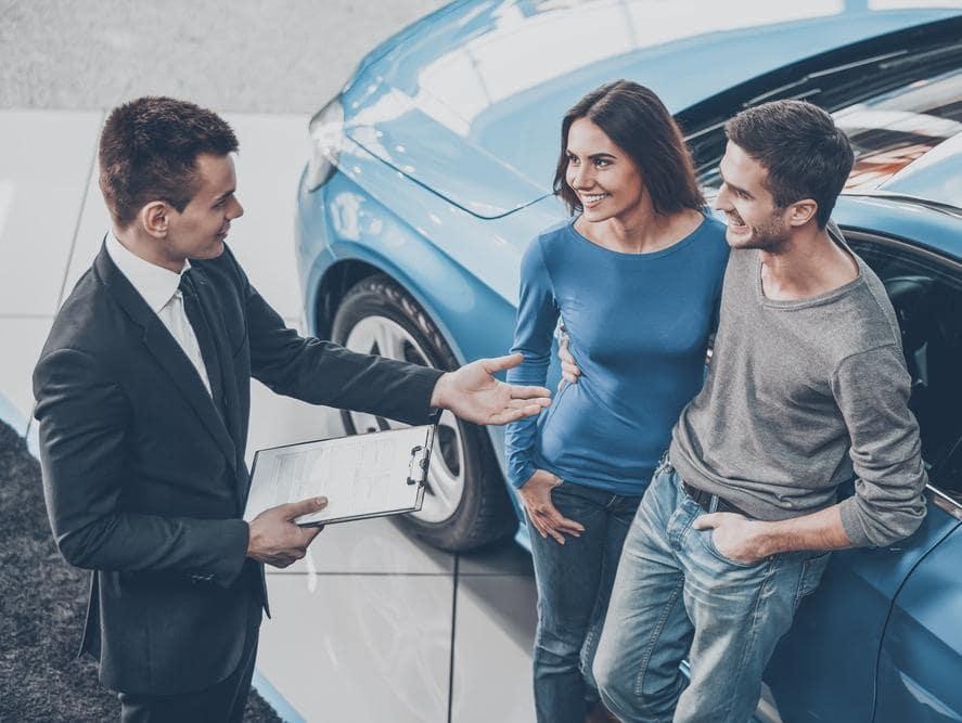Sales consultant talking with couple buying a car