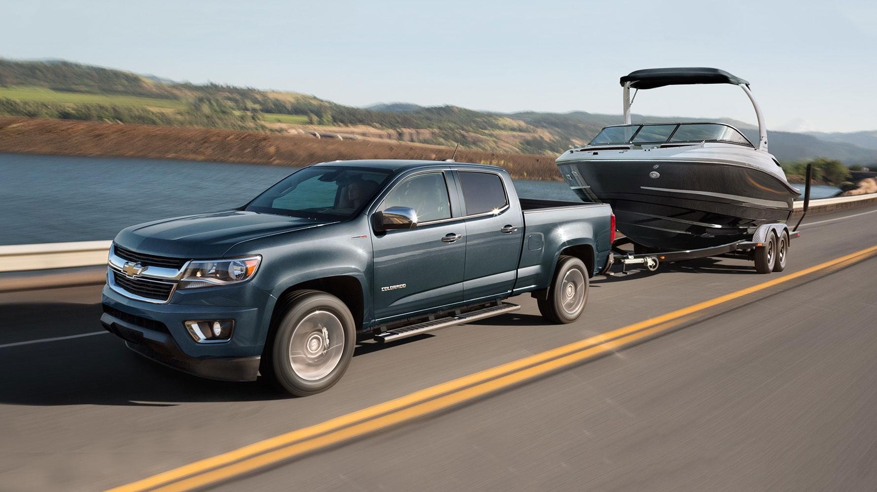 Satin Metallic 2019 Chevy Colorado driving on a road near lake.