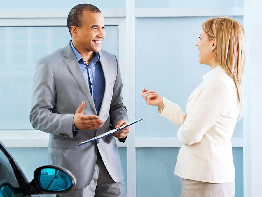 Woman Chatting with Salesperson in Dealership Showroom