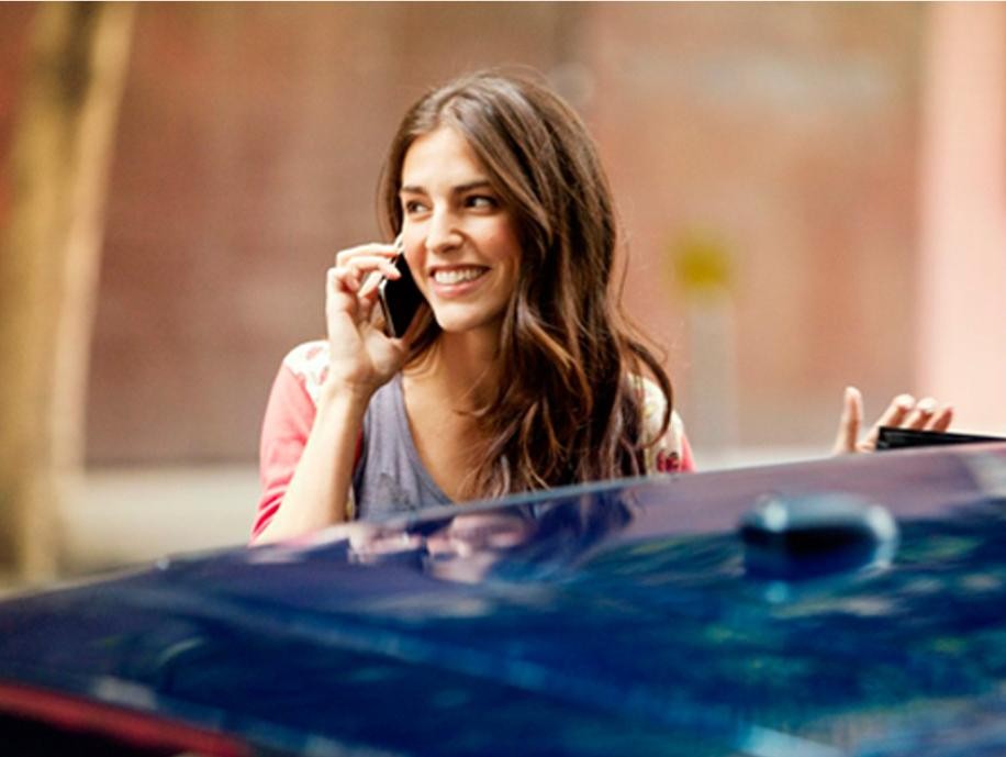 Women talking on her phone while standing next to vehicle