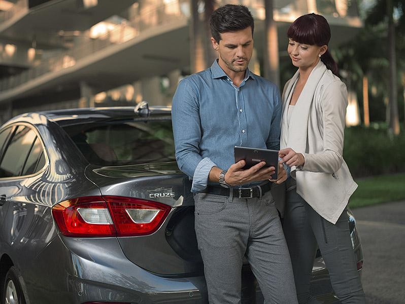 Couple Viewing Tablet Next to Trunk of Chevrolet Cruze