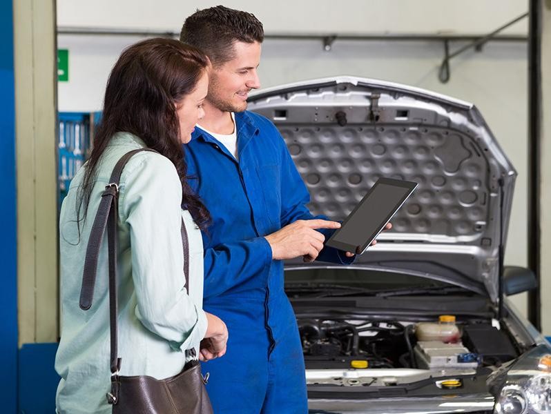 Mechanic explaining issues to customer after car service.