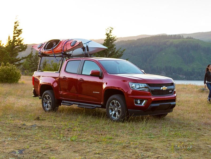 Kayak enthusiasts setting up with their Chevy Colorado trucks by a lake.