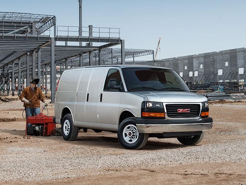 A white GMC Savana Cargo van on a construction site.