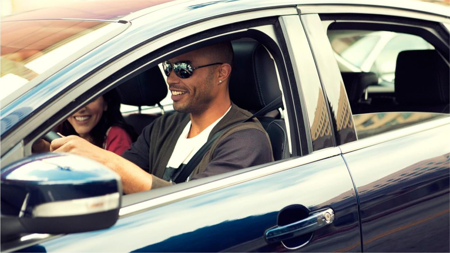 Man sitting in driver seat laughing with women in passenger seat