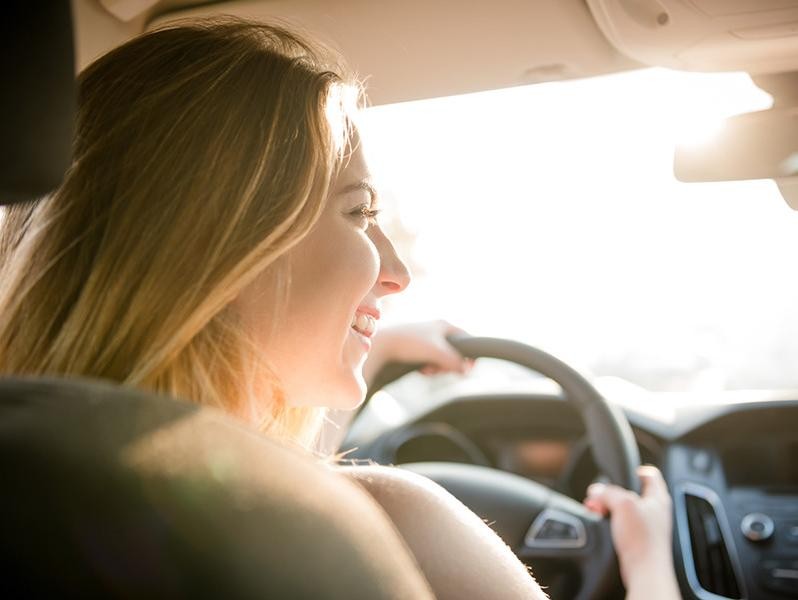 Happy driver driving with vibrant sun on her face.