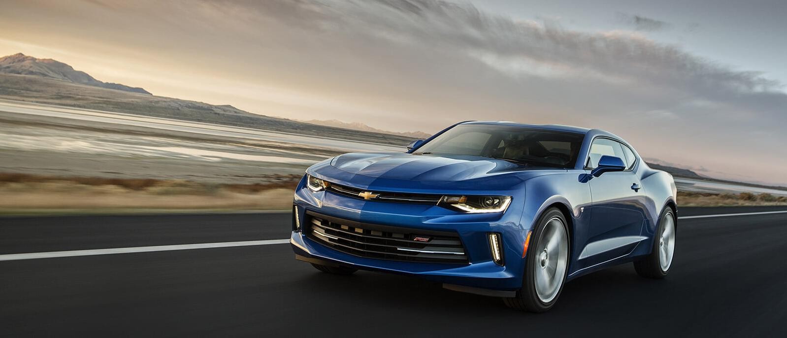 The 2018 Chevy Camaro driving along a desert highway at dusk.