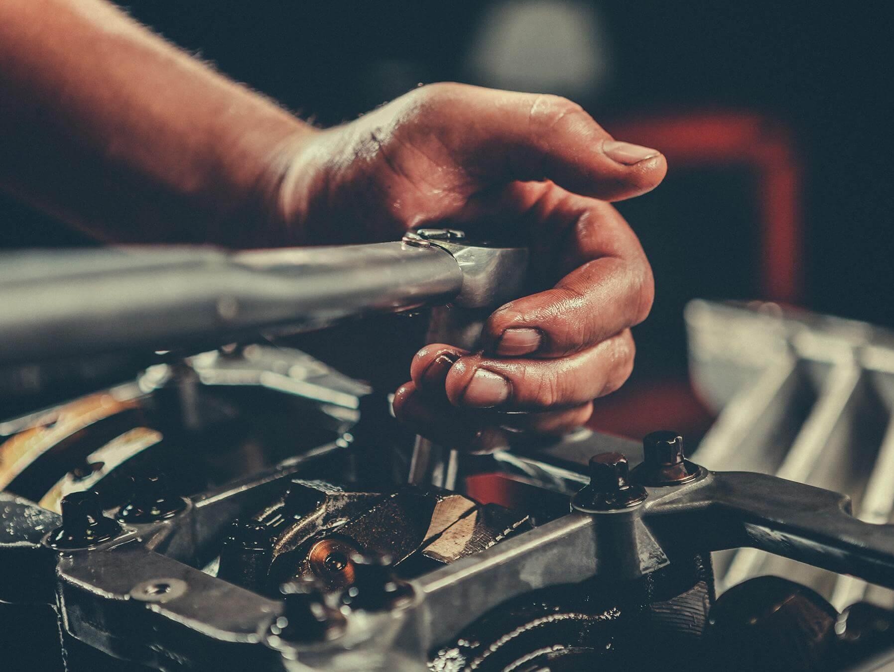 Service technician turning wrench on vehicle engine