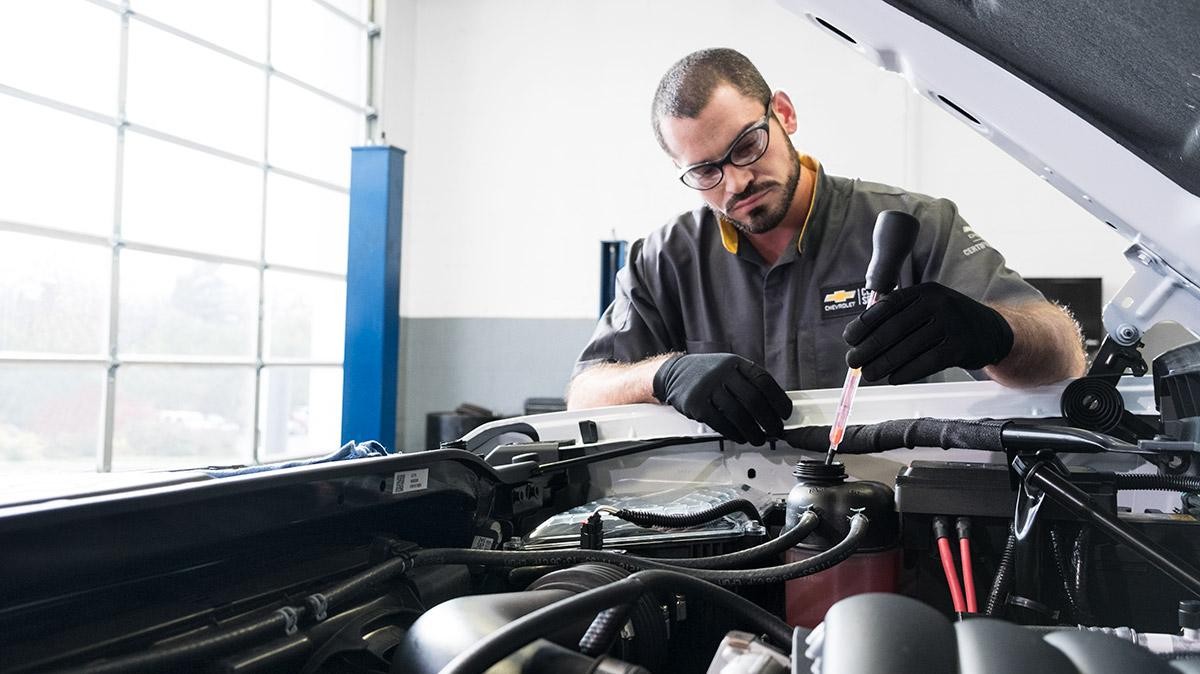 Service technician working under the hood of a car.