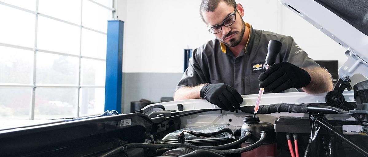 Service technician working under the hood of a car.